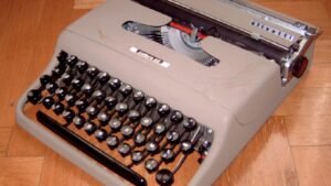 Alte Olivetti-Reiseschreibmaschine auf Holzboden (Symbolbild)