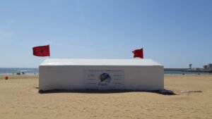 Strand von Agadir mit Wassersport-Verleihstand und marokkanischen Flaggen