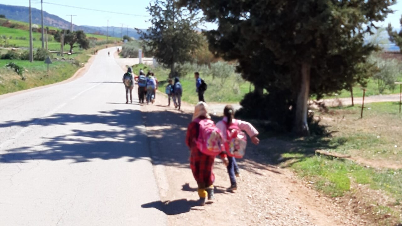 Marokkanische Schulkinder mit Ranzen auf dem Schulweg in einem Dorf