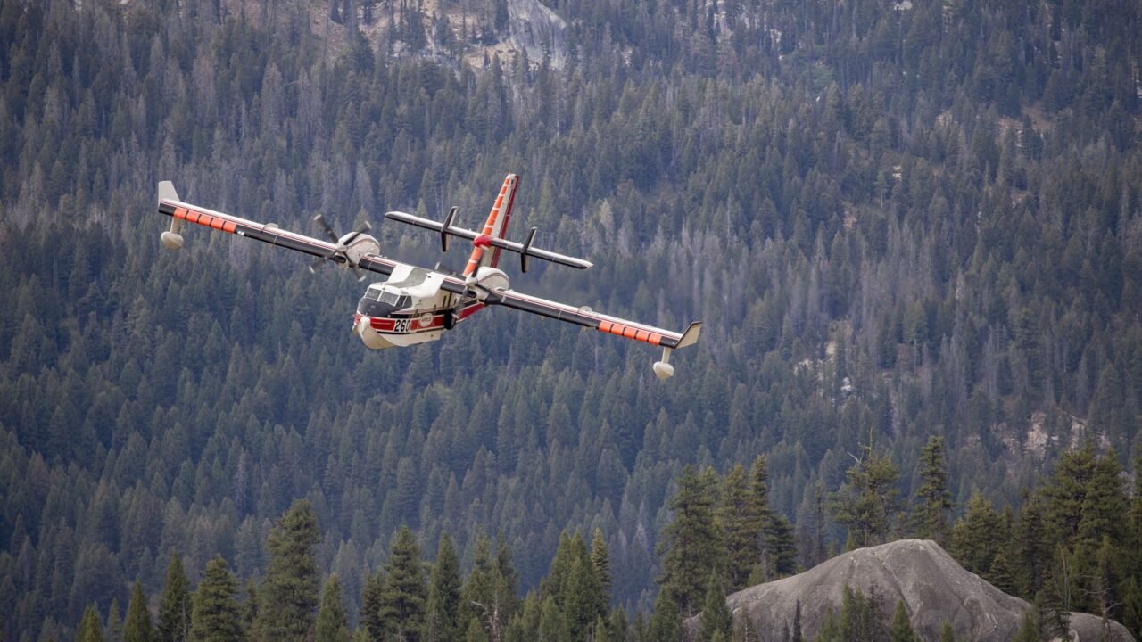 Löschflugzeug vom Typ Canadair im Einsätz über bewaldetem Gelände (Symbolbild)