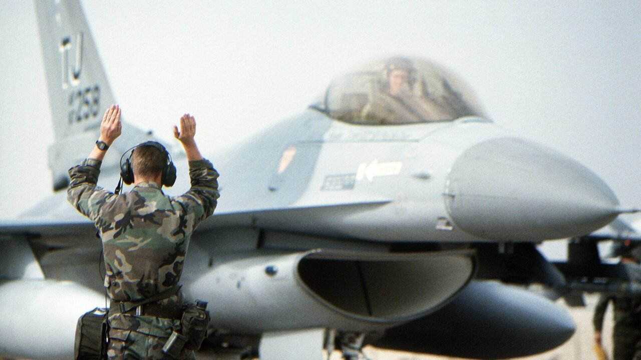 F-16 Fighting Falcon auf dem Rollfeld, ein Einweiser gibt Zeichen (Symbolbild)
