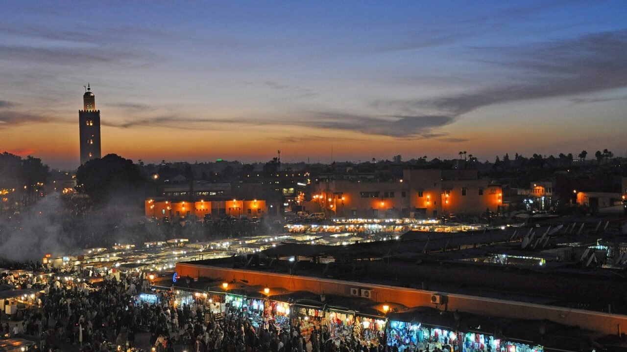 Abendstimmung auf dem Platz Djemaa el-Fna in Marrakesch mit Koutoubia-Minarett und Marktständen